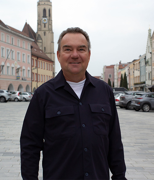 Portrait Foto von Andreas Ganzbeck am Stadtplatz Neuötting mit Kirchturm im Hintergrund.
