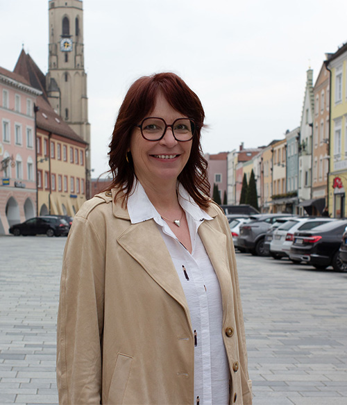 Portrait Foto von Hildegard Kattner am Stadtplatz Neuötting mit Kirchturm im Hintergrund.